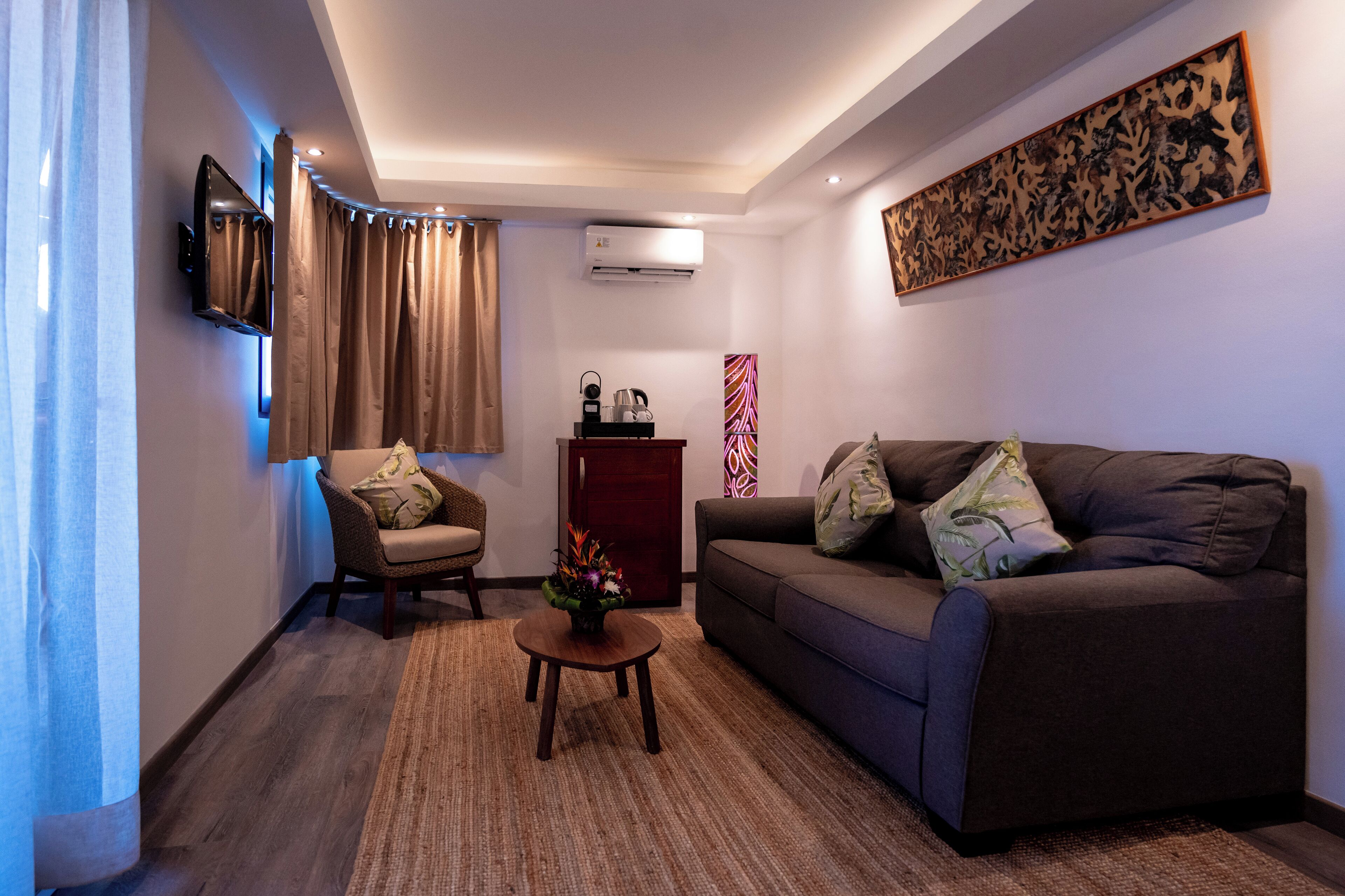 A modern living room with a sofa, armchair, and a small table with a vase.
