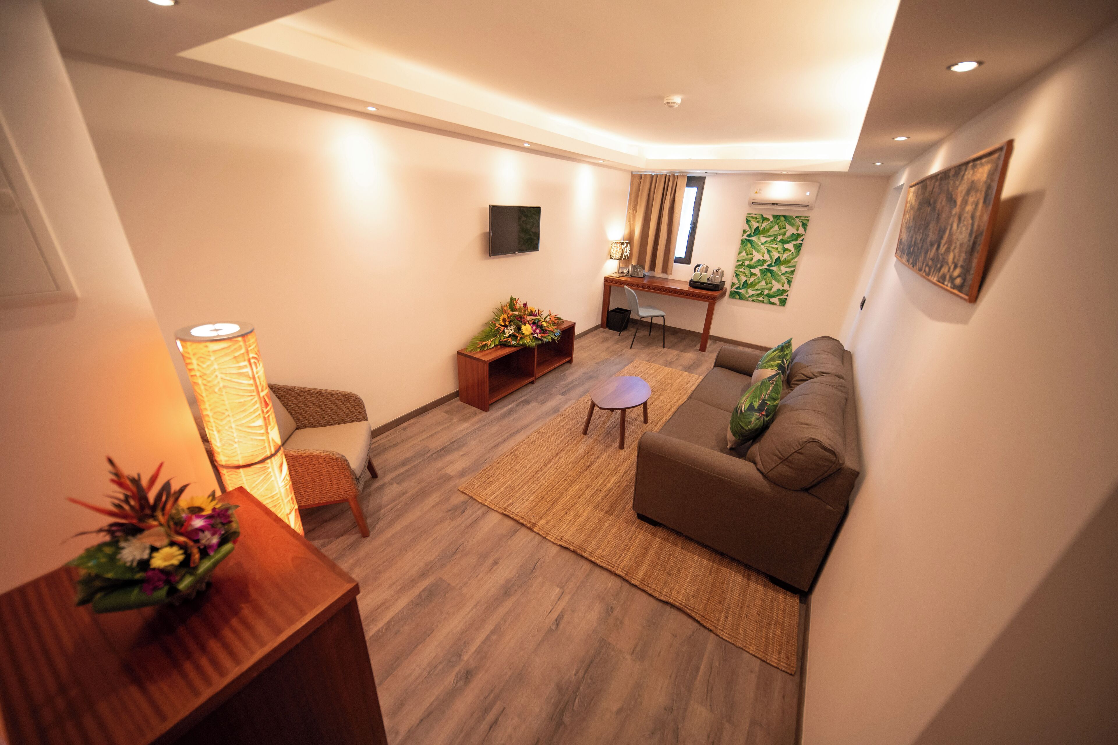 A modern living room with a sofa, a coffee table, a desk, and a TV.