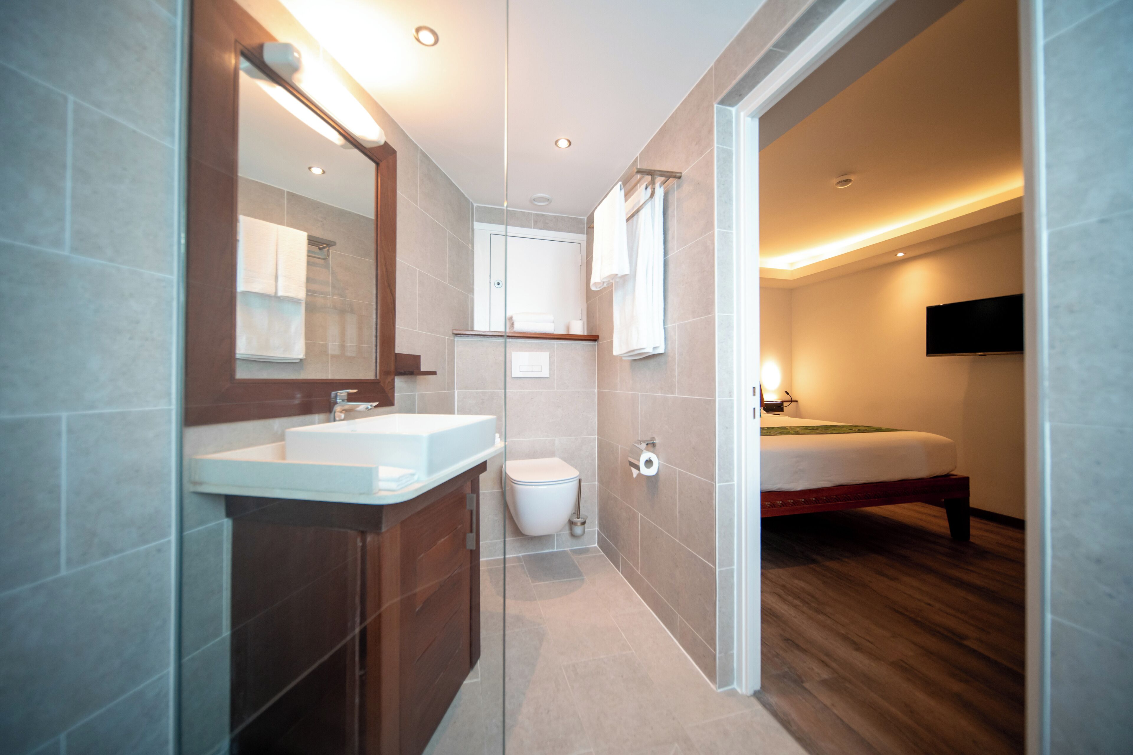 Une salle de bain moderne avec un grand miroir, deux lavabos, des toilettes et une douche.