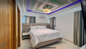 A modern bedroom with a bed, bedside tables, a nightstand, a ceiling light fixture, and a window with curtains.