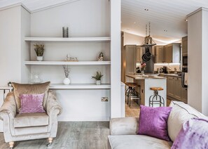 A modern living room with a sofa, armchair, and a built-in shelf unit.