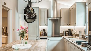 A modern kitchen with a wooden island, stainless steel appliances, and light-colored cabinetry.