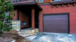 Une maison avec des fondations en pierre, un porche en bois et un garage.