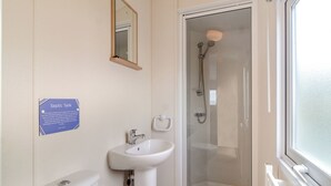 Un baño con lavamanos, inodoro y ducha con mampara de vidrio.