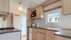 Una cocina compacta con armarios de madera, microondas, tostadora y ventana con vistas.