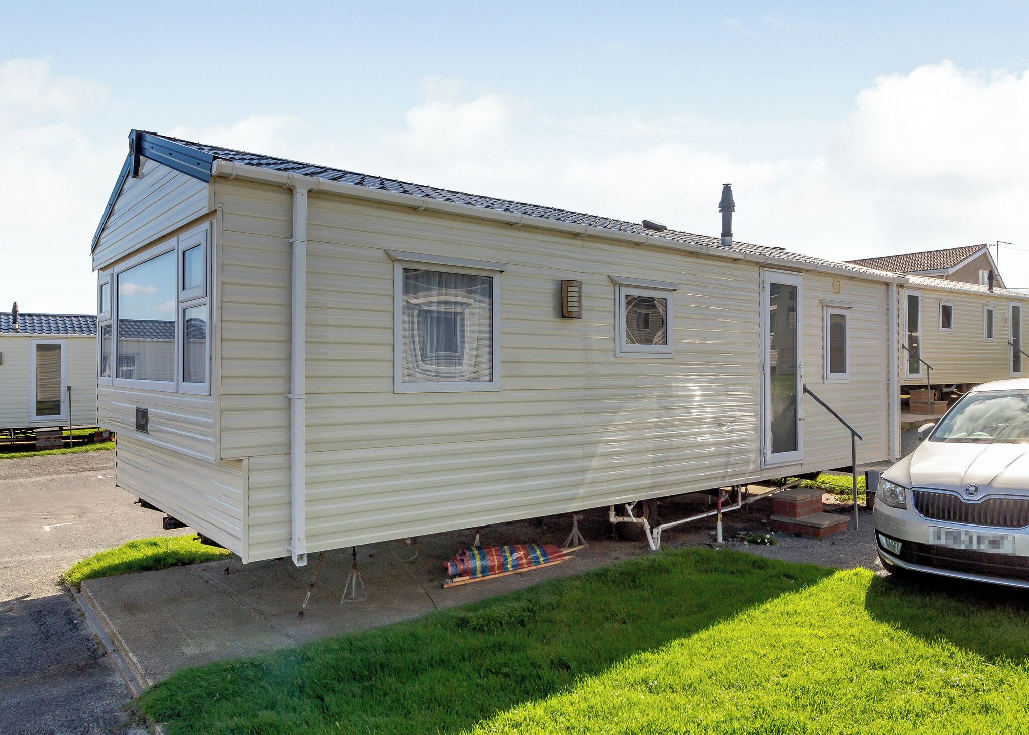 A mobile home with a front door, windows, and a garage door.