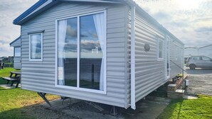Una casa móvil con un ventanal grande, una puerta y un pequeño porche.