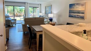 Un salon moderne avec un canapé, une table à manger et des chaises. Une grande fenêtre offre une vue sur l’extérieur.