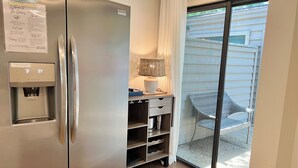 Une petite cuisine équipée avec un réfrigérateur en acier inoxydable, un distributeur d’eau et une petite table avec une lampe.