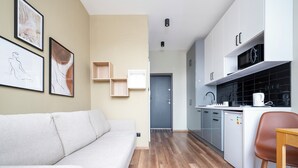 Une cuisine moderne avec des meubles blancs, une table à manger en bois et un fauteuil en cuir marron.