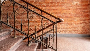 Un escalier orné de rampes en métal ouvragé, avec un mur en briques en arrière-plan.