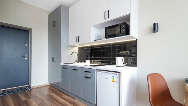 Une cuisine moderne avec des meubles gris, un four à micro-ondes, une machine à café et un lave-vaisselle.