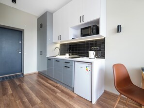 A modern kitchen with grey cabinets, a microwave, a coffee maker, and a dishwasher. - Poznańska Comfy Studio (Łódź)