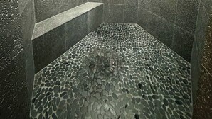 Eine Dusche mit Boden in Kieseloptik und Handbrause.