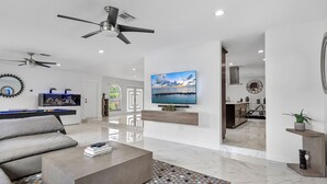 Una sala de estar moderna con un sofá gris, una mesa de centro y un televisor montado en la pared.