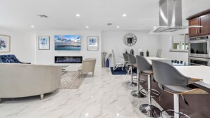 Una cocina moderna con una isla central, taburetes de bar y un horno empotrado.