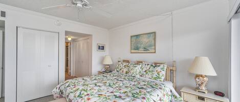 A bedroom with a bed, bedside tables, a ceiling fan, and a nightstand with a lamp.
