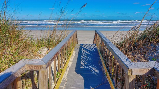 A wooden boardwalk leading to a beach with waves in the background. - About the View at Ocean House 312 (St. Augustine)