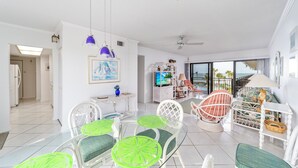 A spacious living area with a dining set, a television, and a balcony with a view. - About the View at Ocean House 312 (St. Augustine)