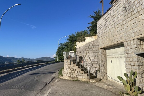 A paved road with a stone wall and a garage door on the right.