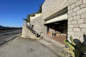 Un edificio in pietra con una scala che conduce a un ingresso coperto, una pianta di cactus e un cielo sereno.