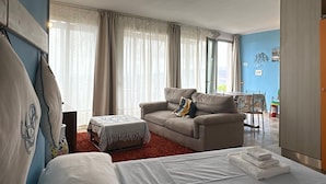 A room with a bed, a sofa, a dining table, and a kitchen area. - Nettuno Apartment (Capoliveri)