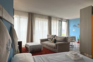 A room with a bed, a sofa, a dining table, and a kitchen area. - Nettuno Apartment (Capoliveri)