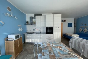 A compact kitchen with white cabinets, a microwave, and a dining area with a table covered in newspaper.