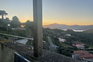 A coastal landscape with a road, buildings, and a mountain range in the background. - Nettuno Apartment (Capoliveri)