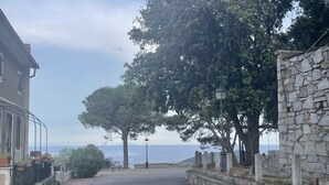 Un chemin pavé mène à un mur de pierre d’où l’on a une vue sur la mer.