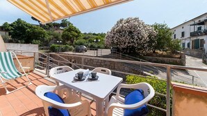 Une terrasse avec une table et des chaises, une chaise à rayures et un arbre en fleurs.