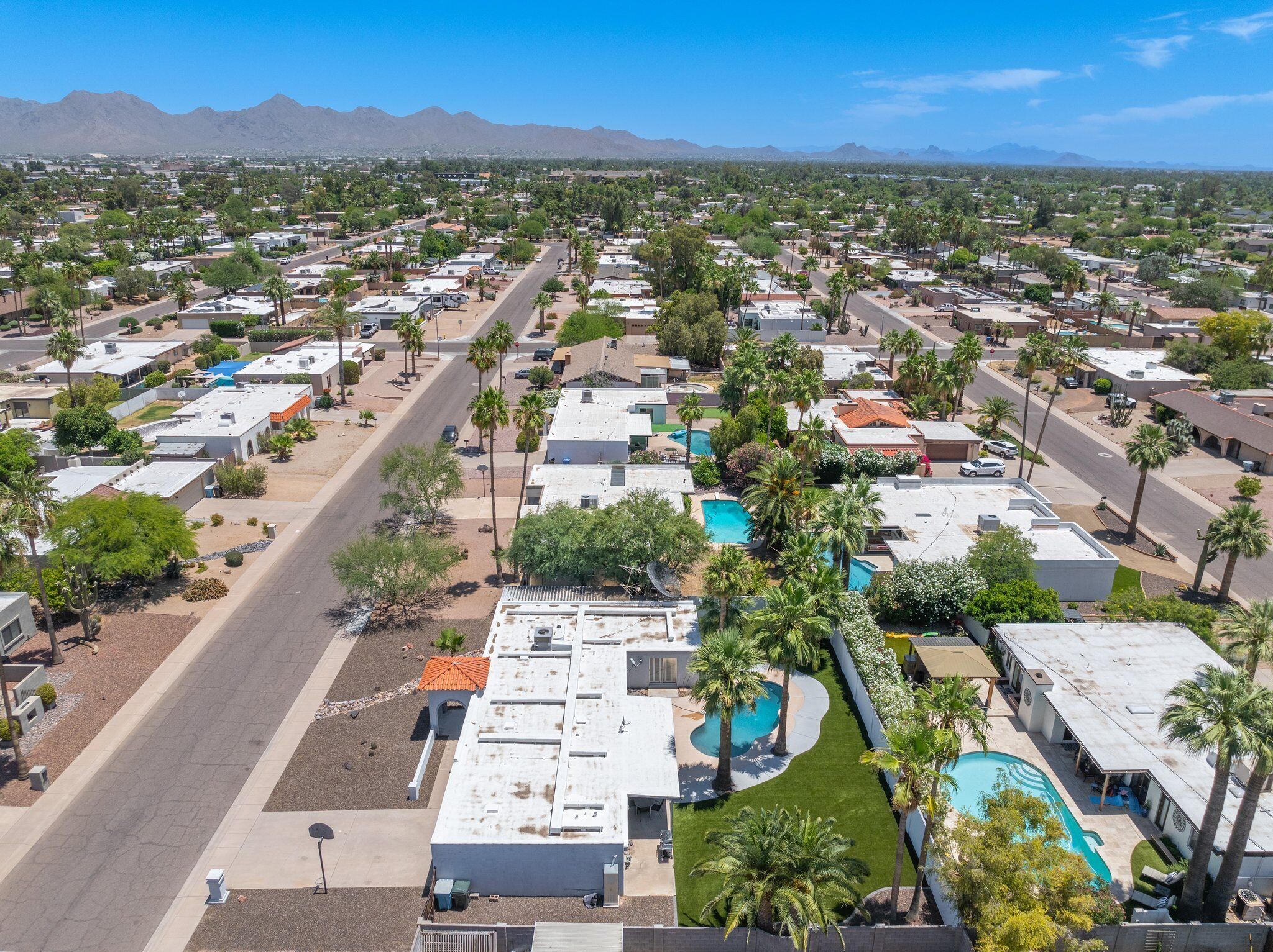 A residential area with multiple houses, a central road, and a swimming pool.