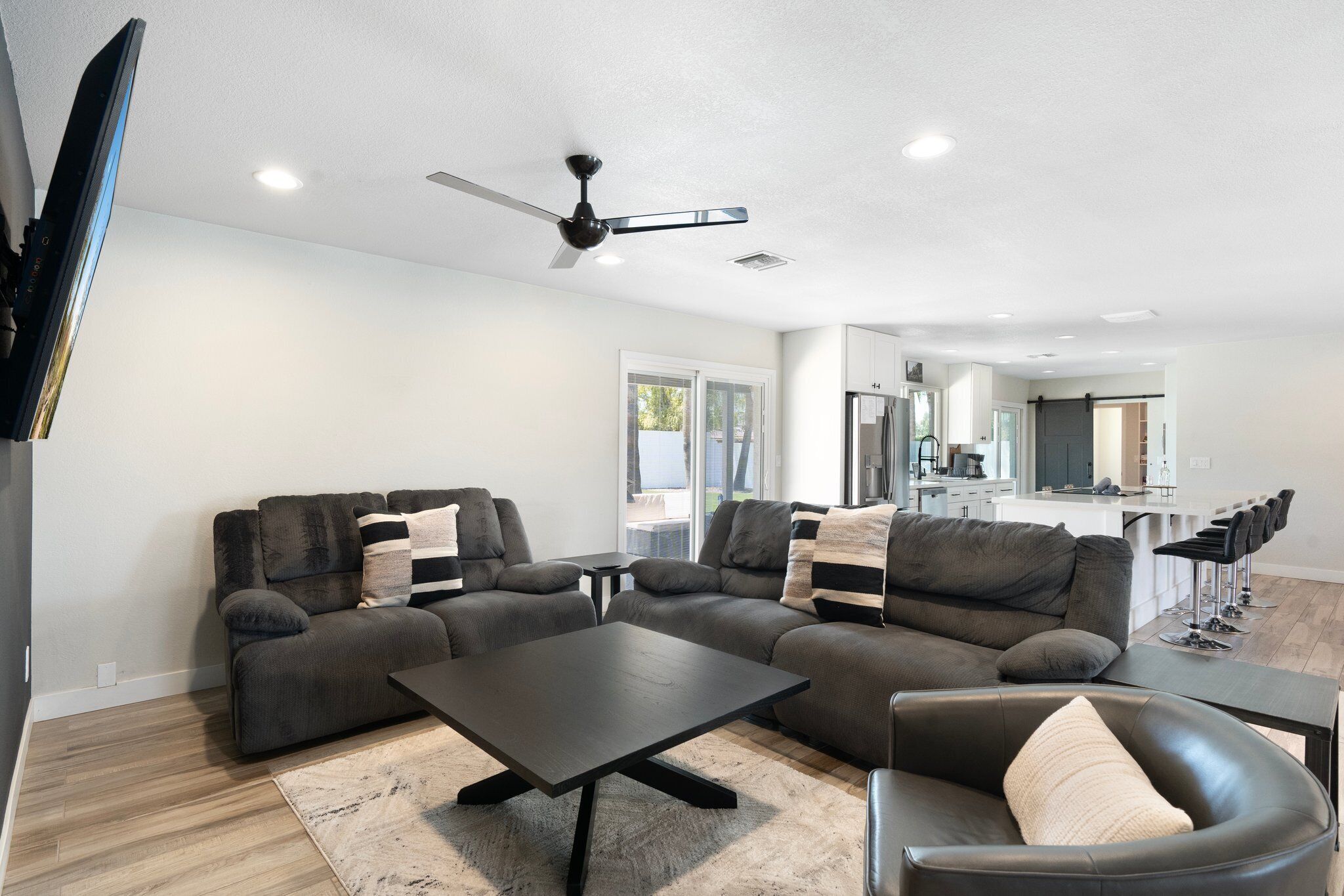 A modern living room with a sectional sofa, a coffee table, and a black leather chair.