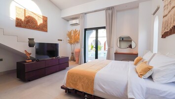 Un dormitorio moderno con cama, televisor en una cómoda y vista a una piscina al aire libre.
