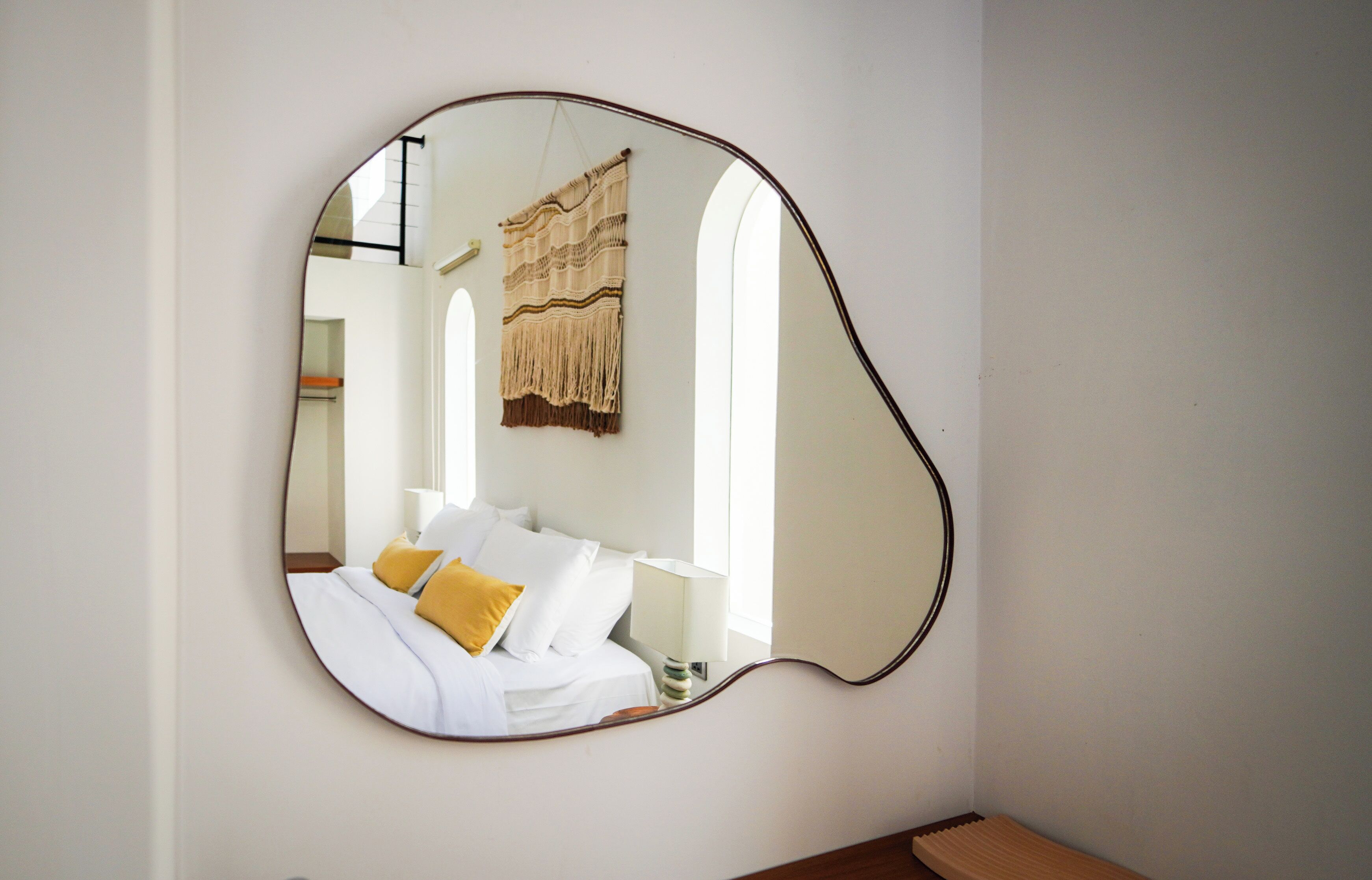 A room with a bed, a bedside table, and a wall-mounted mirror.