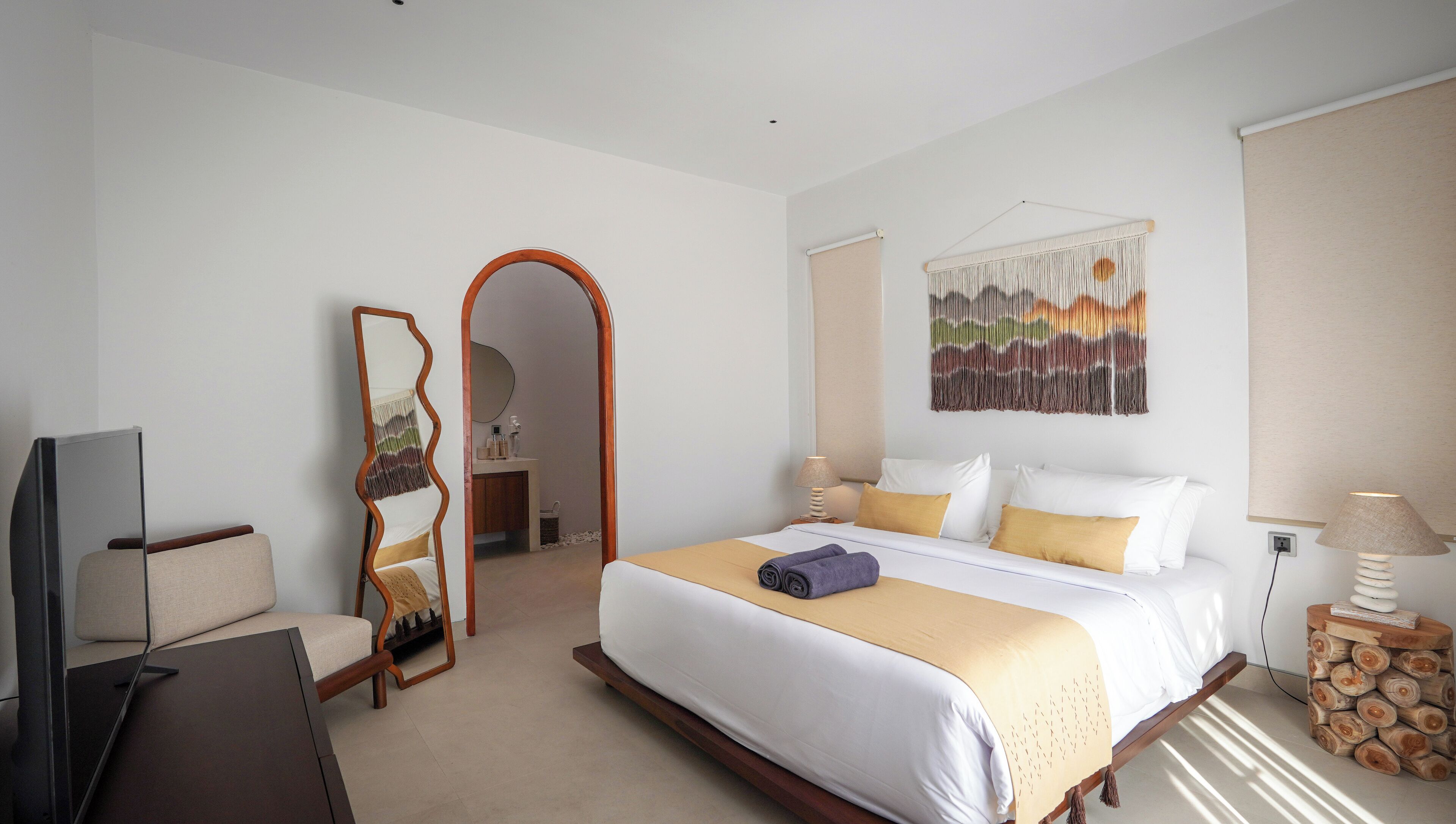 Ein Hotelzimmer mit einem großen Bett, einem Fernseher, einem Schreibtisch und einem Spiegel.
