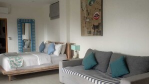 A modern living room with a bed, a sofa, and a wall-mounted air conditioner. - Triple 888  Suites (Labuan Bajo)