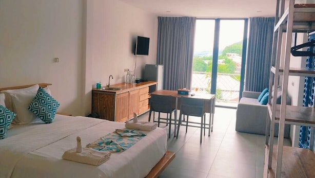 A modern hotel room with a large bed, a desk, and a view of the outdoors. - Triple 888  Suites (Labuan Bajo)