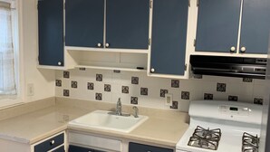 Una cocina con gabinetes azul oscuro, un lavamanos blanco y una estufa blanca.