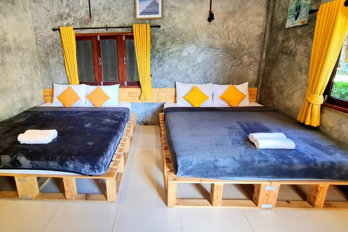 Una habitación con dos camas de madera, cada una con una toalla blanca sobre la cama.