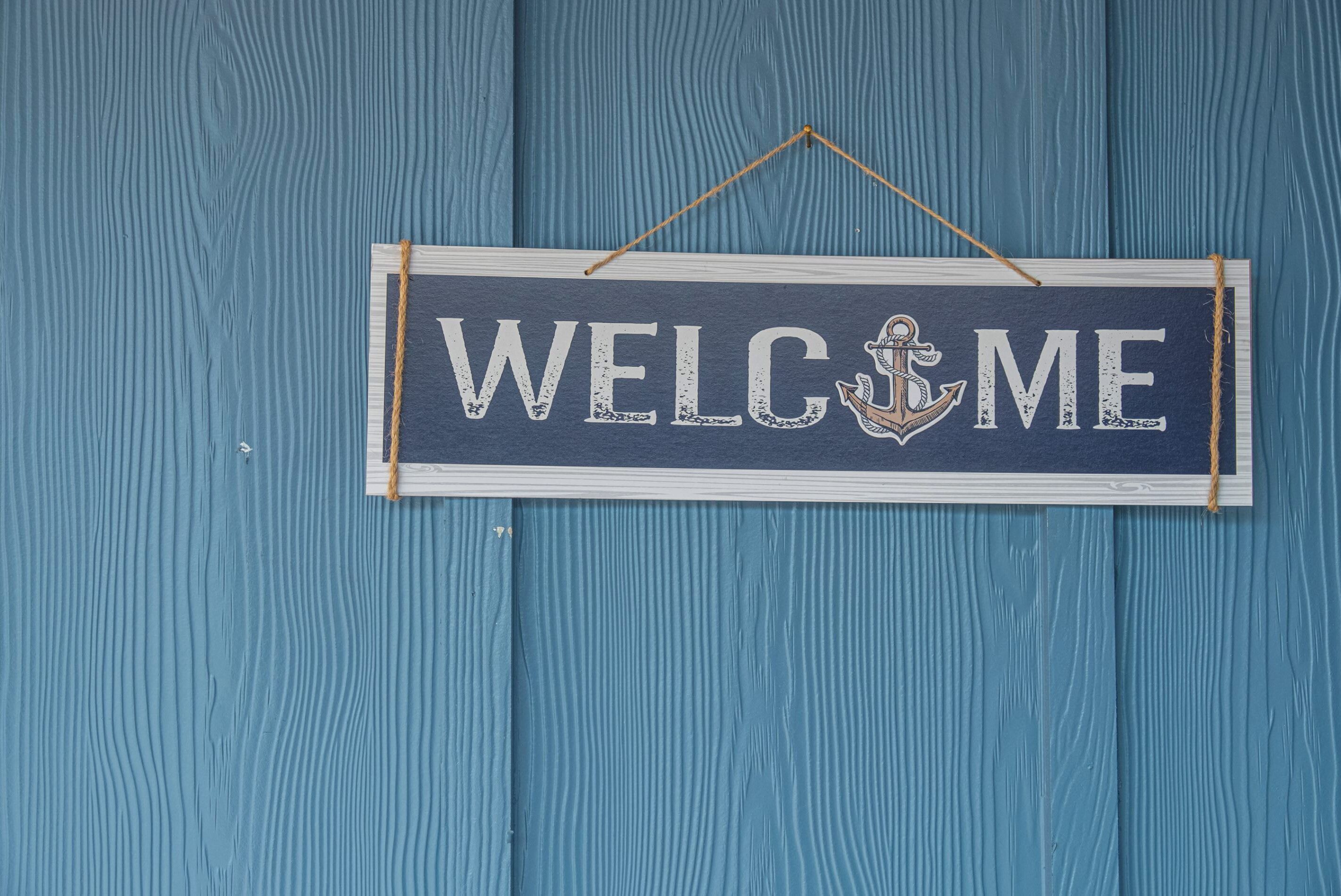 A 'WELCOME' sign with an anchor, hanging on a blue wooden wall.