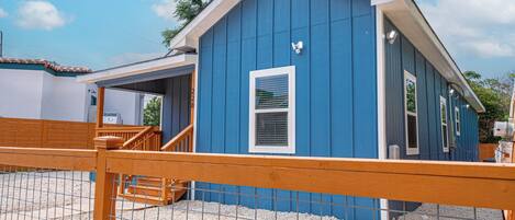 A blue building with a white window and a wooden fence in front.