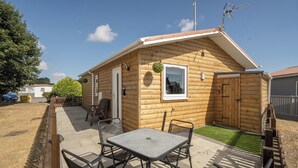A wooden cabin with a patio, a table, and chairs.
