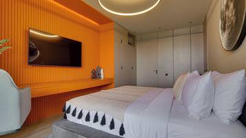 Ein modernes Schlafzimmer mit einem großen Bett, einem an einer orangefarbenen Wand montierten Fernseher und einem Kleiderschrank mit Schiebetüren.