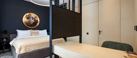 A modern bedroom with a bed, a desk, and a wardrobe.