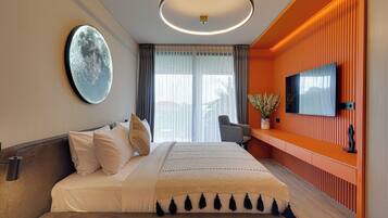 A modern hotel room with a large bed, a flat-screen TV, a desk with a chair, and a large window with curtains.