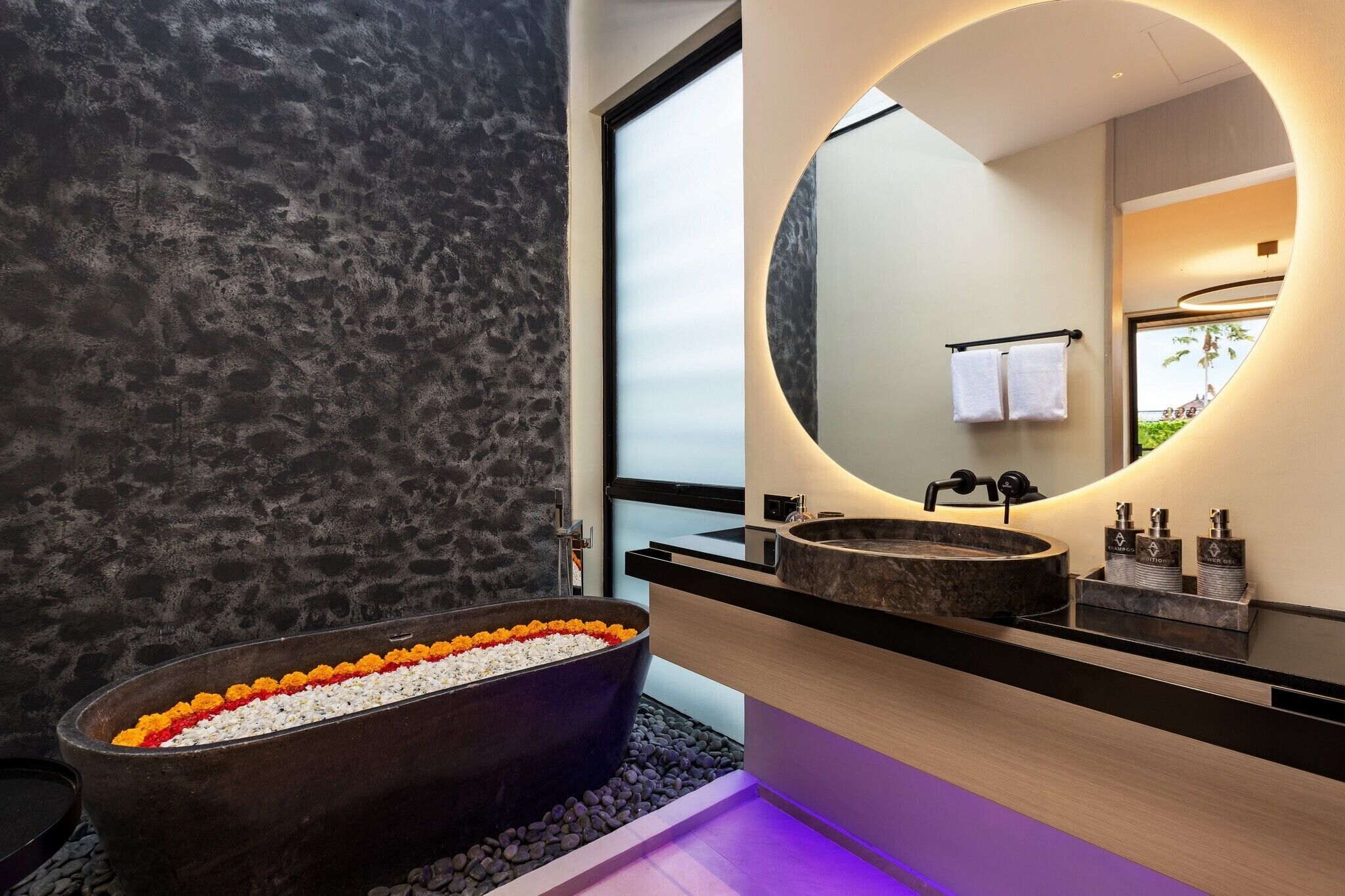 A modern bathroom with a freestanding bathtub, a large mirror, and a vanity with two sinks.