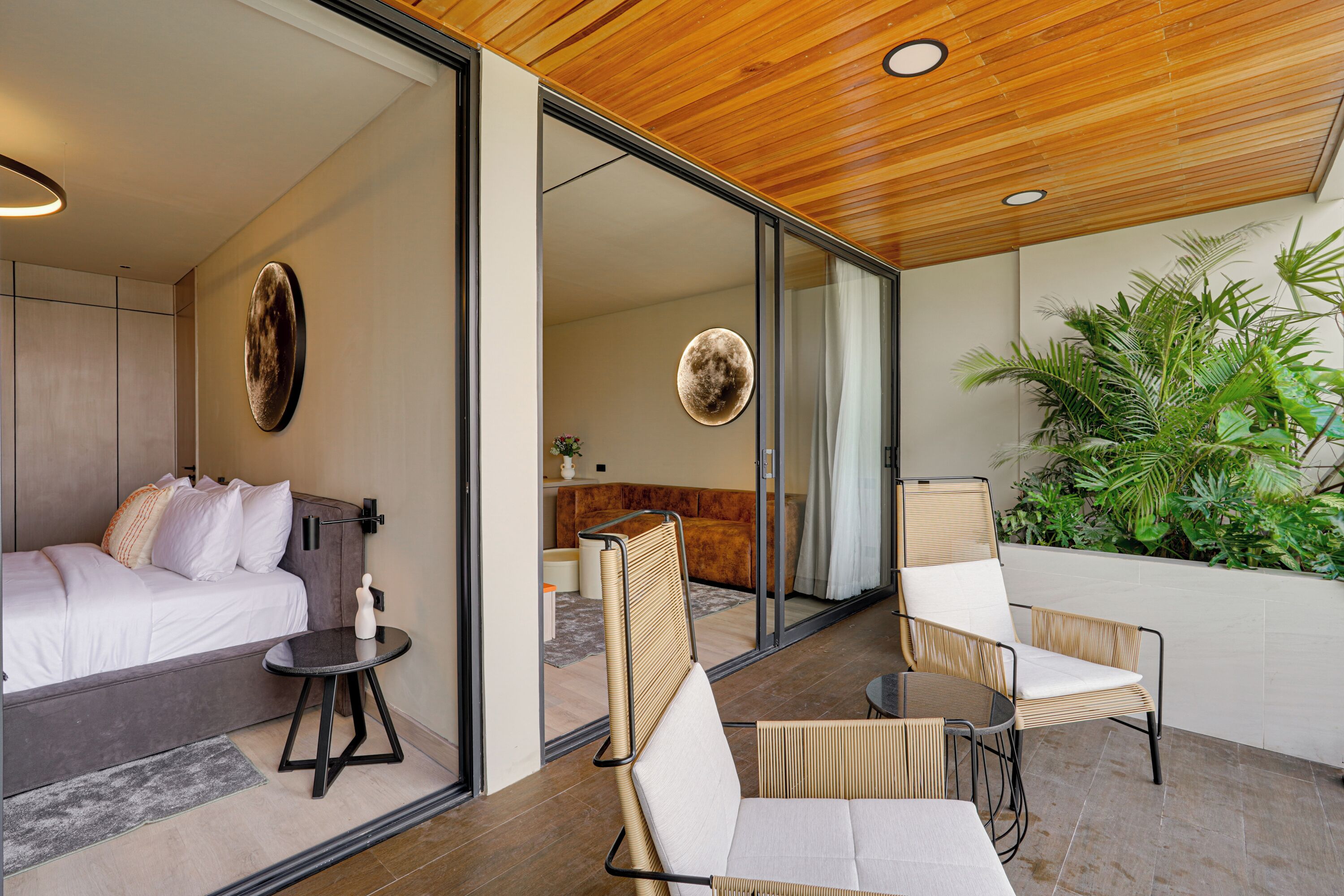 A modern hotel room with a bed, a small table, and a seating area with chairs.
