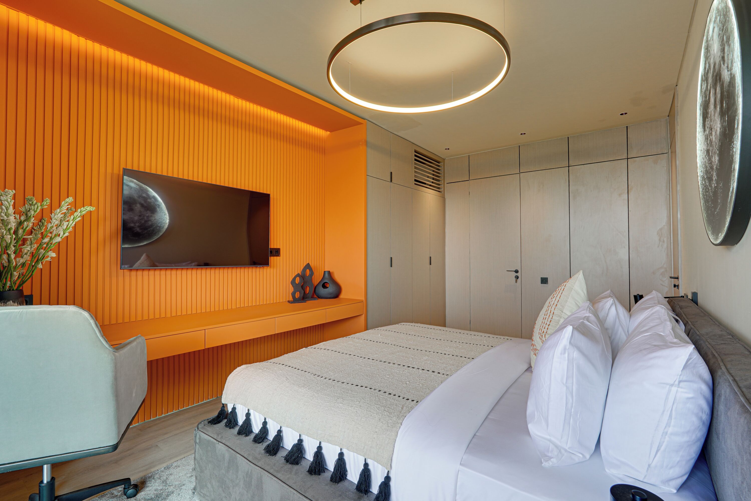 A modern bedroom with a large bed, a desk, and a wall-mounted TV.