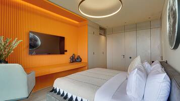 Un dormitorio moderno con una cama grande, un escritorio y un televisor instalado en la pared.